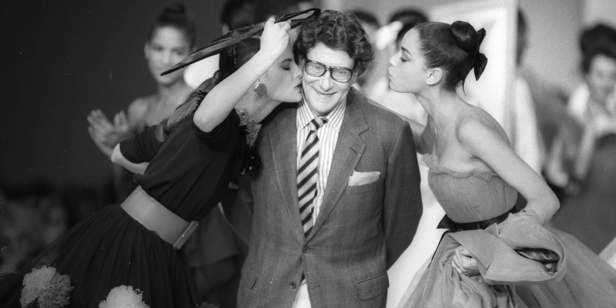 French designer Yves Saint Laurent is kissed by models at the end of his fashion show in Paris October 21, 1987. REUTERS/Luc Novovitch (FRANCE) BEST QUALITY AVAILABLE - RTR21B68